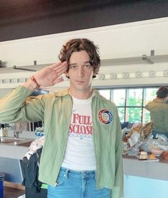 a man standing in front of a kitchen counter holding his hand up to his head