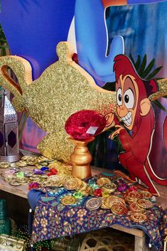 a table topped with lots of gold and red decorations next to a giant blue balloon