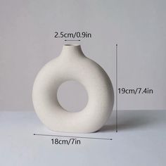 a white vase sitting on top of a table next to a measuring tape and ruler