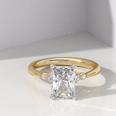 an engagement ring with a princess cut diamond in the center and three diamonds on each side