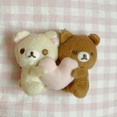 two teddy bears laying next to each other on a pink and white checkered blanket