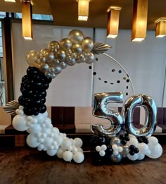 the balloon arch is decorated with black, white and silver balloons