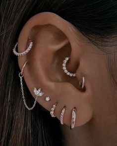 a close up of a person with ear piercings and chains on their ears,