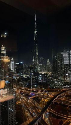 the city skyline is lit up at night with many lights and buildings in the foreground