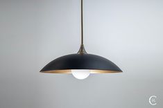 a black and gold pendant light hanging from a ceiling fixture in a room with white walls