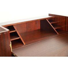 a wooden desk with two open shelves on top and one closed drawer at the bottom