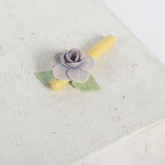 a small flower sitting on top of a white table next to a yellow candle holder