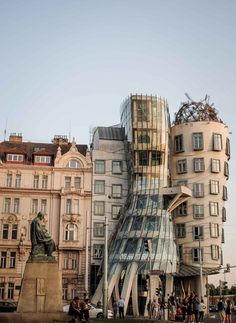 people are walking around in front of some buildings and a large building with a glass facade