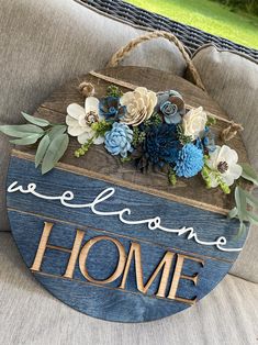 a wooden sign that says welcome home with flowers on it