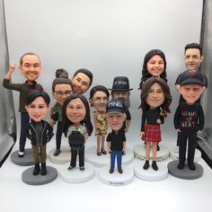 a group of bobble heads are posed in front of a white backdrop