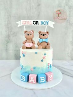 two teddy bears sitting on top of a baby shower cake