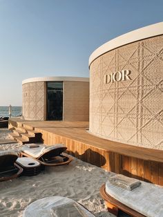 the exterior of a building with wooden steps leading up to it and beach chairs on the sand