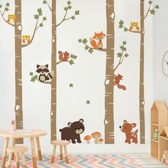 a child's room with wall decals that include trees, animals and leaves