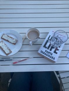 there is a plate with cake and a cup of coffee on it next to a book