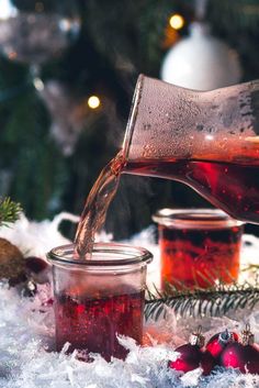 tea being poured into glass jars with christmas decorations in the background