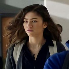 a woman with long hair is walking through an airport