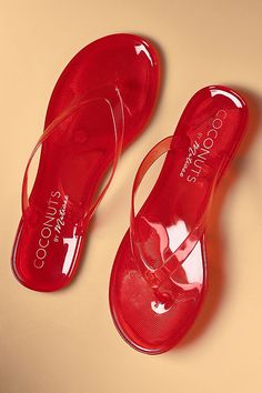 a pair of red sandals sitting on top of a beige table next to each other