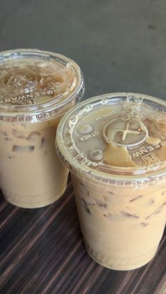 two iced coffees sitting on top of a wooden table