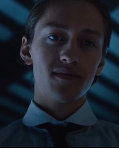 a young man wearing a white shirt and black tie looking at the camera with an intense look on his face