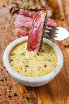 a piece of meat sticking out of a bowl of soup with a fork in it