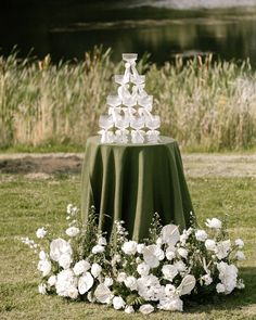 a cake on top of a table with white flowers in front of water and grass