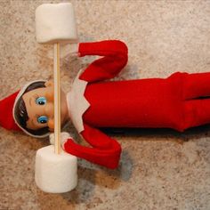 an elf is laying on the floor with marshmallows in front of him