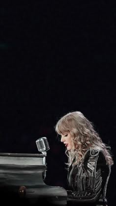 a woman sitting at a piano with a microphone in front of her and the background is black