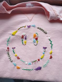 a t - shirt with the letter o on it is decorated with flowers and leaves