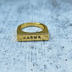 This is a flat top gold plated ring with 90's vibes that reads "KARMA" in cute uppercase font. It's great to wear alone or stacked in multiples. Get it for a cute subtle boost of motivation or gift it to the woman who inspires you to make the world better for all. All rings come beautifully and simply packaged in a box and bow ready for gifting. ABOUT THE JEWELRY• Choose between gold plated brass, gold plated sterling silver (vermeil) and sterling silver.• For custom text, please add at checkout.• The vegan ink used to darken the lettering is semi-permanent.• Each ring is handmade to order for you and a little different due to the nature of hand stamping. CARE INSTRUCTIONS• It is advisable to remove your ring during hand washing.• It is not recommended to sleep, shower or exercise in stamp 90's Vibes, 90s Vibes, Brass Gold, Gold Plated Rings, Semi Permanent, Flats Top, Gold Plated Sterling Silver, In A Box, Hand Washing