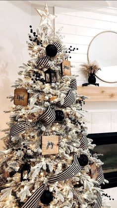 a white christmas tree decorated with black and gold ribbon, ornaments and wooden tags on it