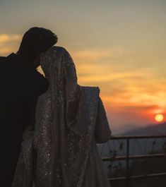 a man and woman standing next to each other at sunset