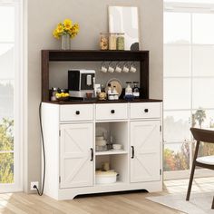 a kitchen with a white cabinet and yellow flowers on the top shelf, next to a dining room table