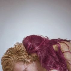 a man and woman with red hair looking at each other's eyes while they both have their heads close to one another