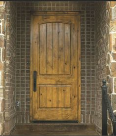 a wooden door sitting on the side of a brick wall next to a set of stairs