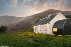 a small white house sitting on top of a lush green hillside