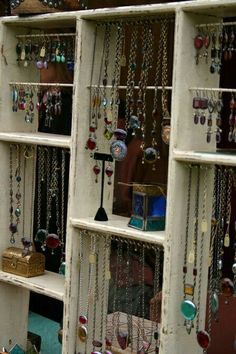 a display case filled with lots of necklaces and jewelry hanging from it's sides