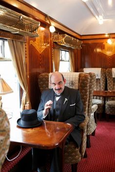 a man in a suit and hat sitting at a table with a top hat on it