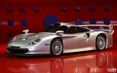 a silver sports car sitting on top of a red floor