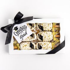 a box filled with assorted pastries wrapped in black ribbon on top of a white table