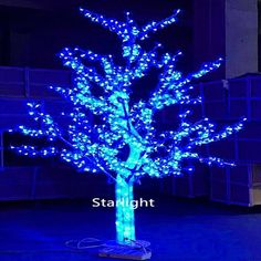 a blue lighted tree in the middle of a dark room with white lights on it