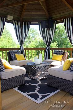 a covered porch with wicker furniture and yellow pillows