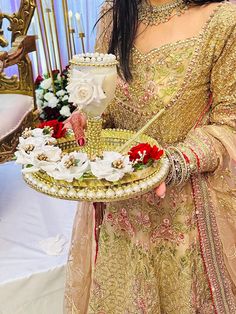 a woman is holding a tray with flowers on it and a cake in the middle