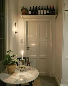 a table with two wine glasses on it and some bottles in front of the door