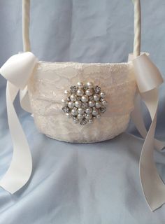 a white flower girl basket with pearls and ribbons