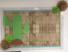 a bulletin board with a cactus and pom - poms on the bottom half