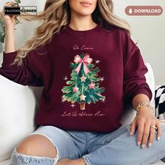 a woman sitting on a couch wearing a christmas tree sweatshirt