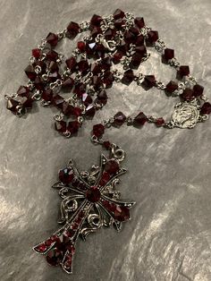 Black plated with red Siam colored crystals. It is hypoallergenic. It has a clasp so that you can wrap around and use it in multi ways. Like all my crosses on my rosaries there are crystals on both sides so that if it turns, you can see crystals on either side. Total must have!