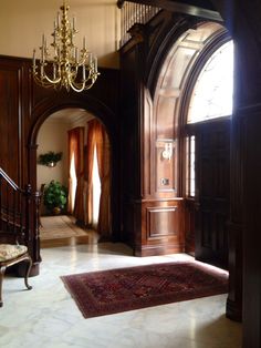 an ornate entry way with chandelier and rug on the floor in front of it