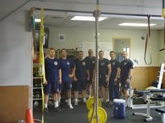 a group of men standing next to each other in front of a gym equipment area