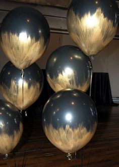 several metallic balloons are stacked on top of each other in front of a wooden floor